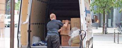 Mitarbeiter belädt einen Transporter mit zu entsorgenden Gegenständen.