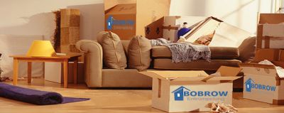 Hausrat in einem ehemaligem Wohnzimmer, verpackt in Kartons mit dem Logo von Bobrow Entrümpelungen.